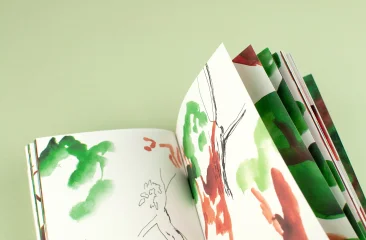 Tentoonstelling Omslag. Een geopend schetsboek met groene en rode aquarellen van bomen en takken.